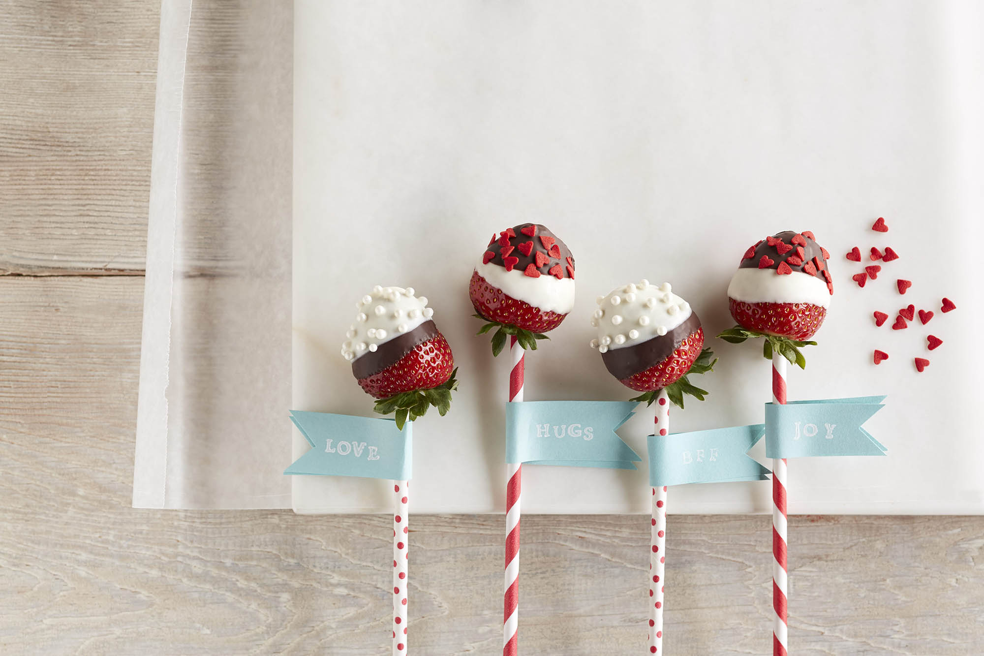 Chocolate covered strawberry pops with sprinkles and patterned sticks 